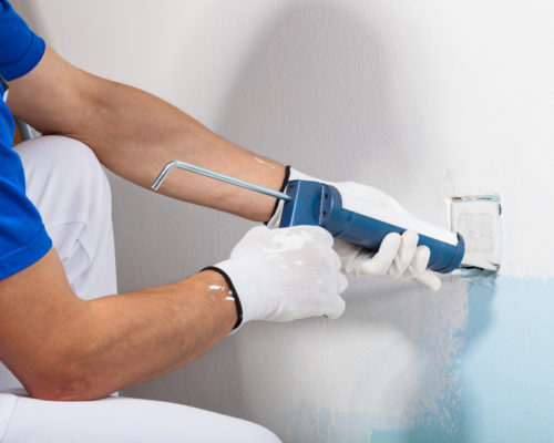 Close-up Of Professional Workman Applying Silicone Sealant With Caulking Gun on the Wall